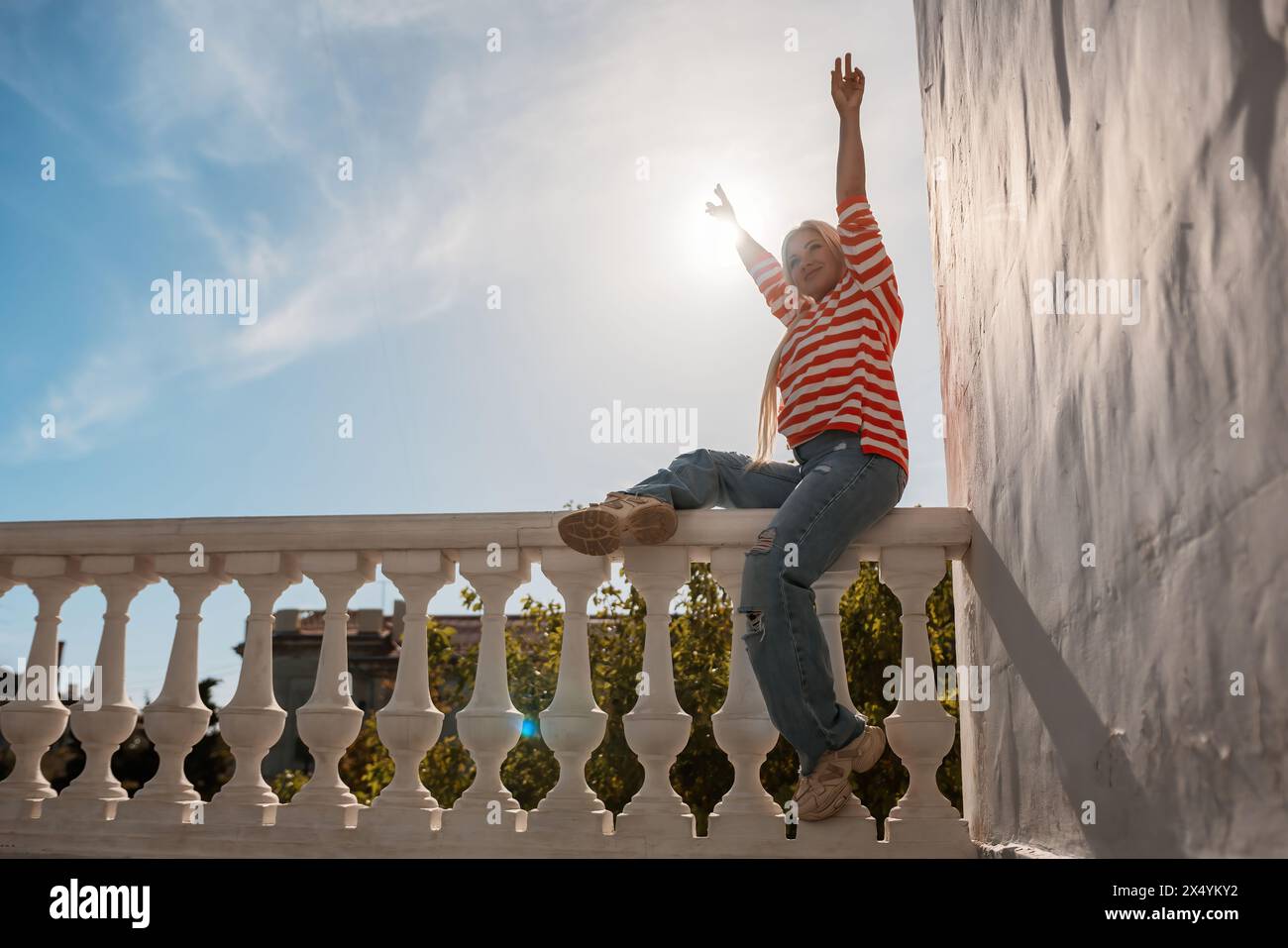 Arm On Railing A woman is sitting on a railing with her arms raised in the air. The ...