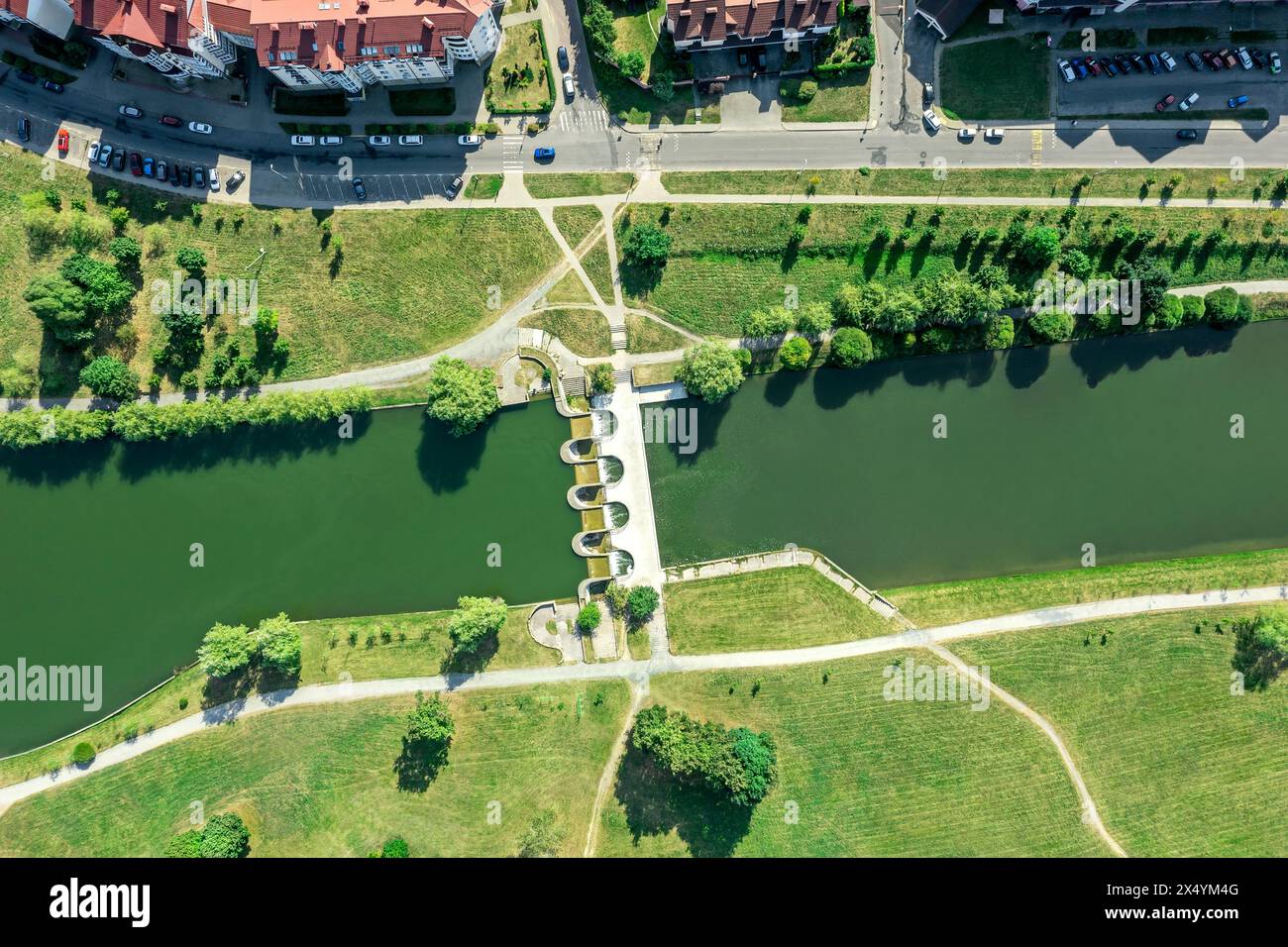 aerial view of city residential area near the river with small dam in sunny summer day. Stock Photo