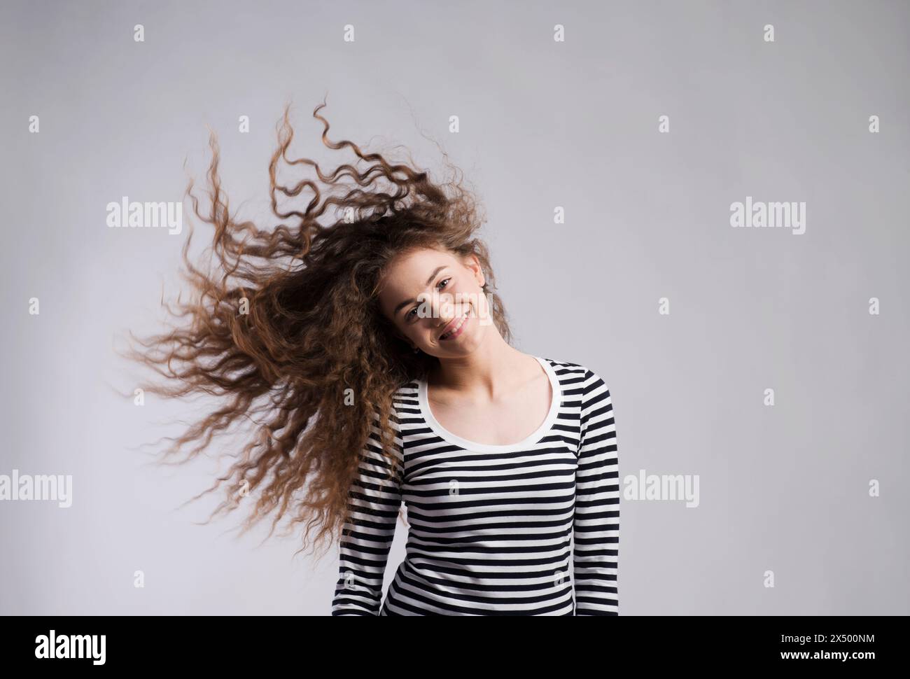 Portrait of a gorgeous teenage girl with curly hair, blowing in wind ...