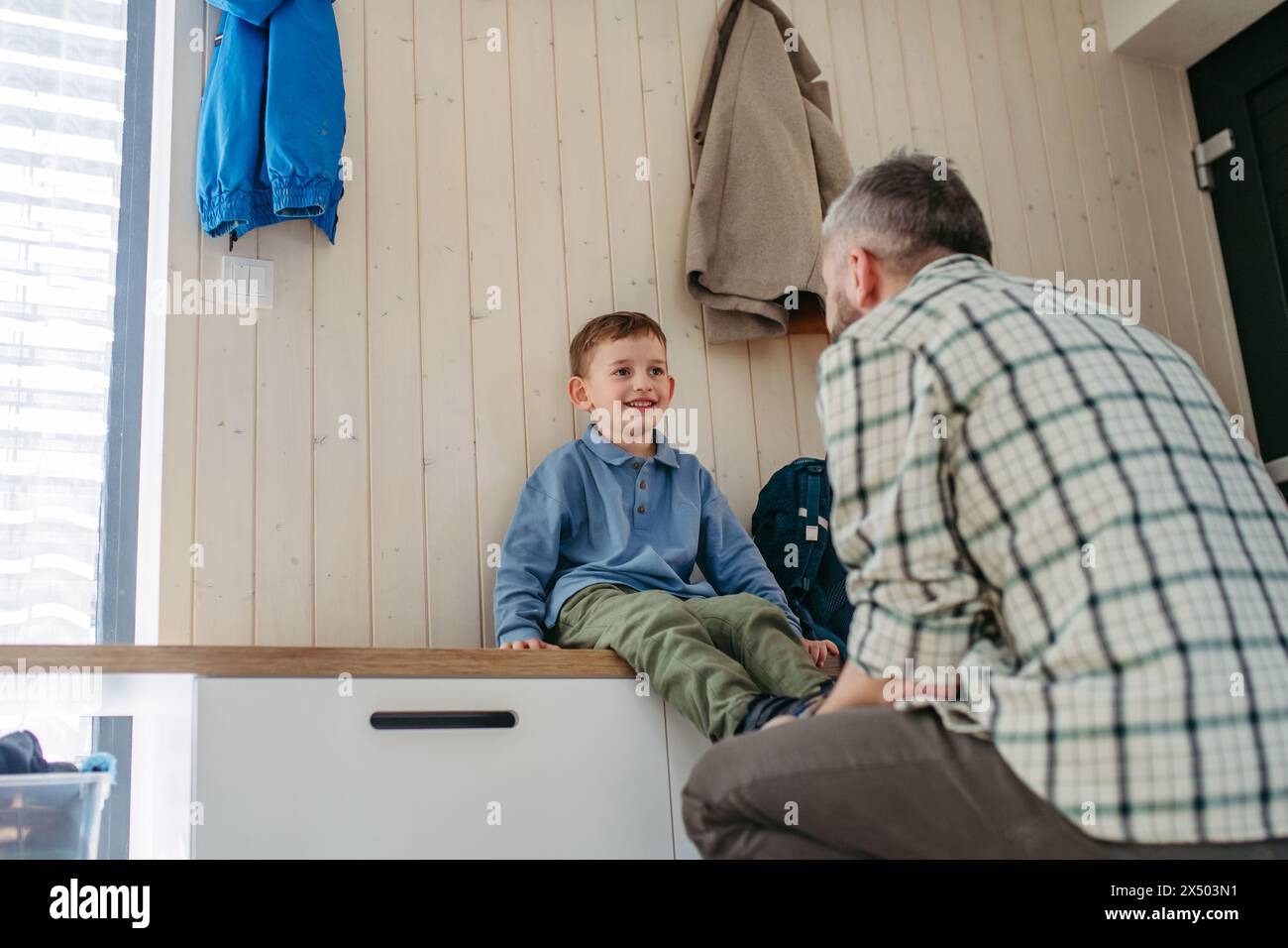 Father helping son get ready for kindergarten, preschool. Putting shoses on. Stock Photo