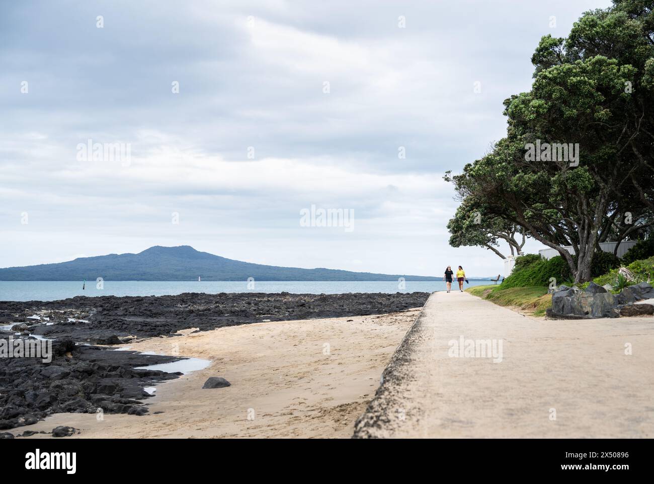 People walking on the beach. Rangitoto Island in the background; Milford Beach. Auckland. Stock Photo
