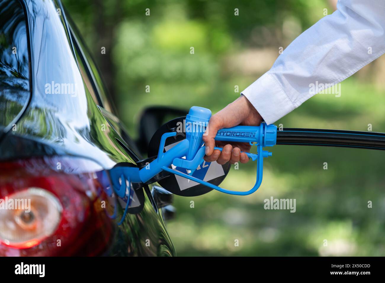 Refueiling Car Man holds a hydrogen fueling nozzle. Refueling car with hydrogen fuel ...