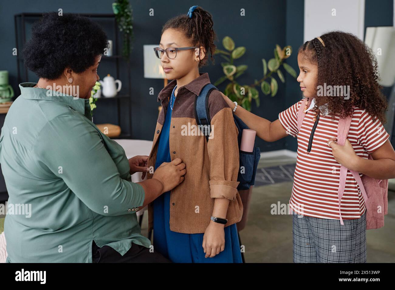 Side view portrait of Black senior woman helping girl with backpack ...