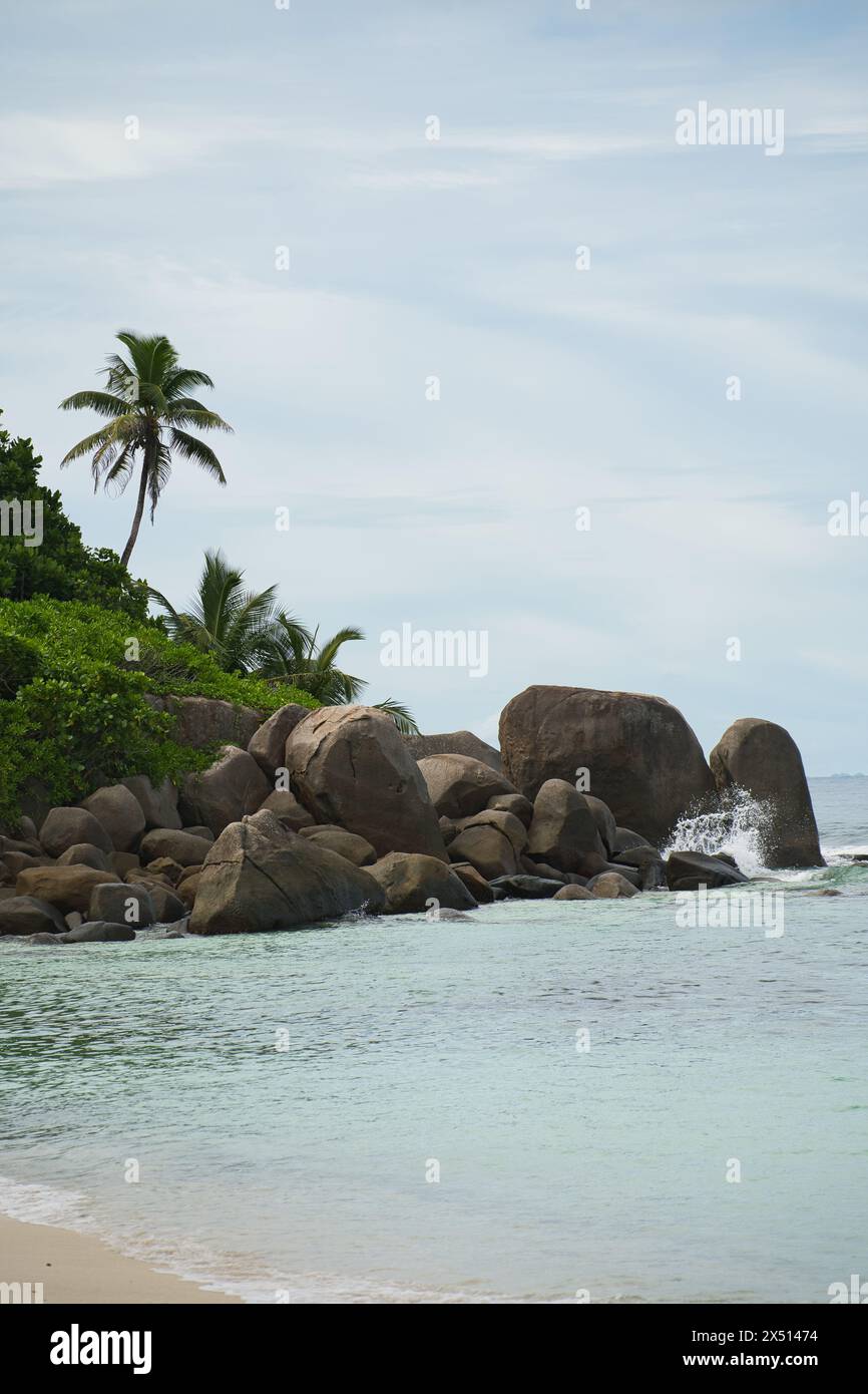 Granite stones and trees near white sandy beach of anse forbans, Calm sea, Mahe Seychelles Stock Photo