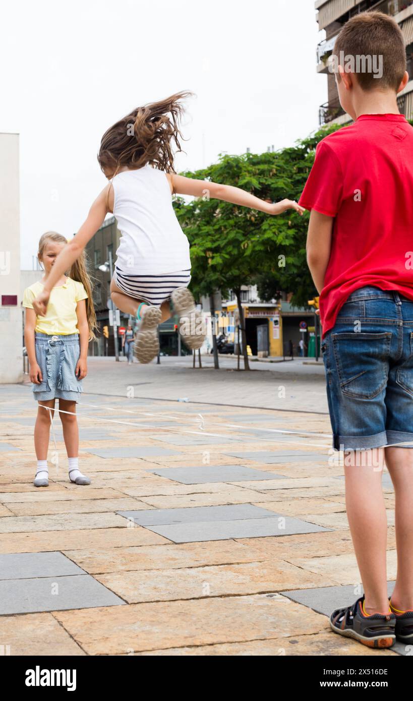 Blonde Girl jumps over rope on the sidewalk in the city in summer Stock ...