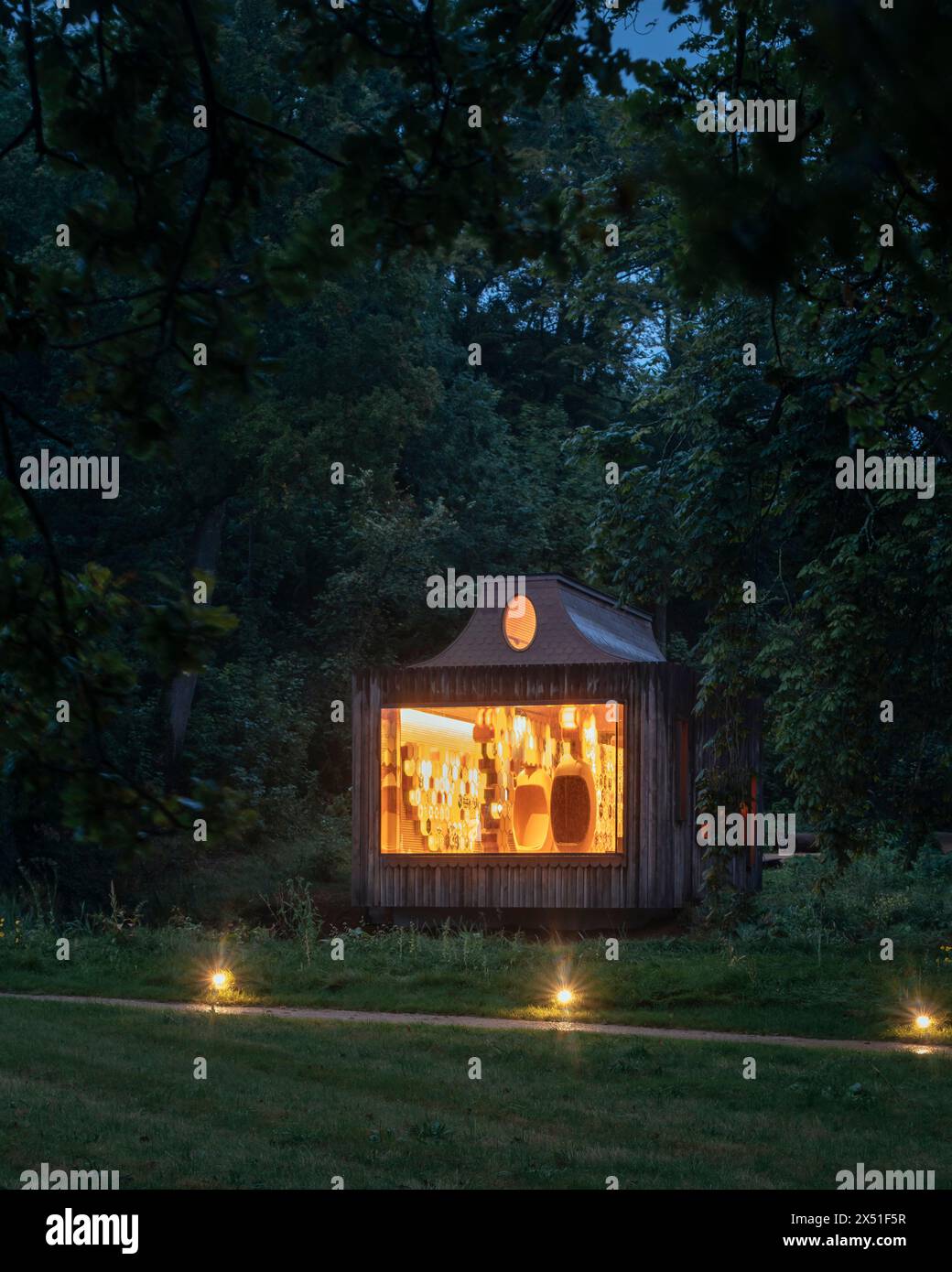 The Apiary pavilion seen at dusk from across a field, surrounded by ...