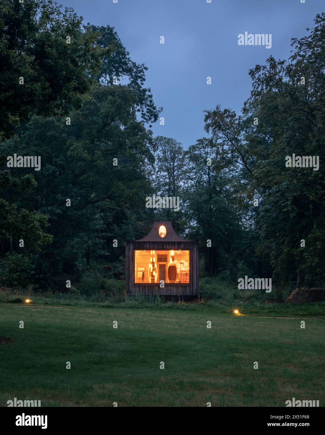 The Apiary pavilion seen at dusk from across a field, surrounded by ...