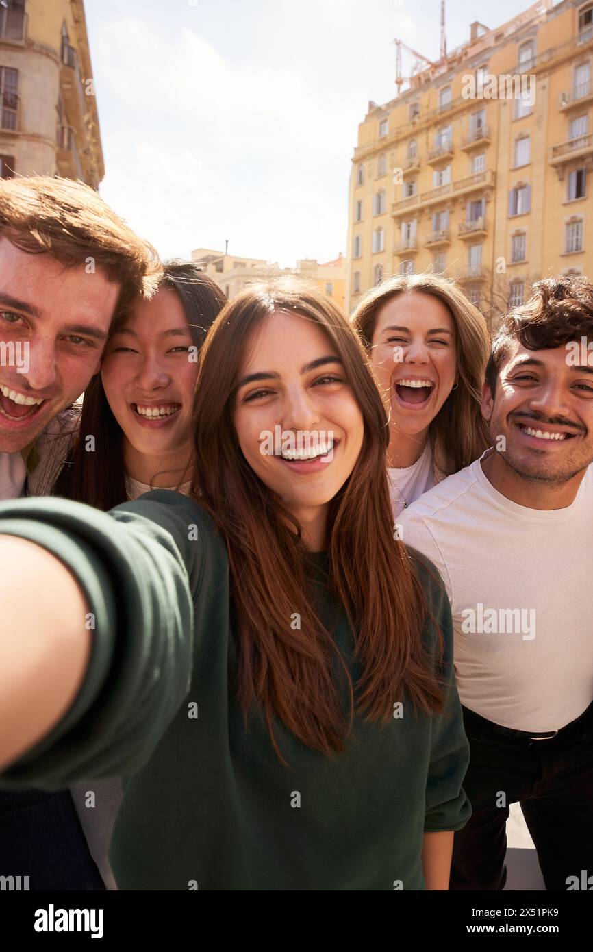 Crowd of young people happy smiling and having fun taking selfie together in front of building. Stock Photo