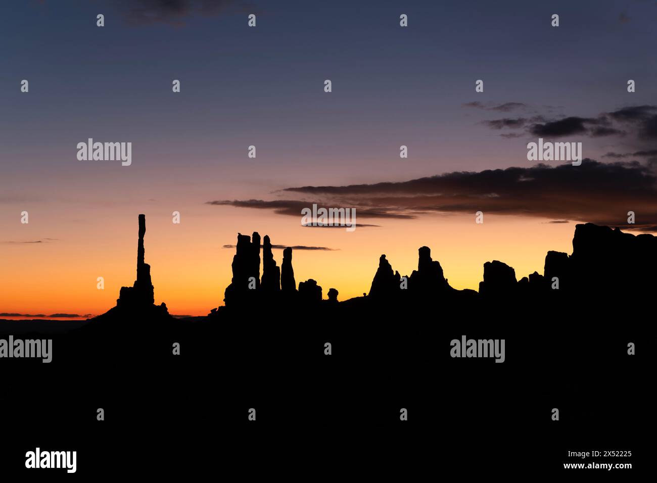Sunrise behind Monument Valley's famous totem pole and nearby spires