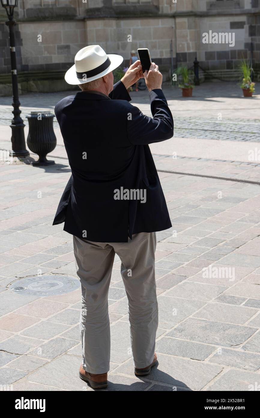 Man on the street captures photograph on mobile device. Stock Photo