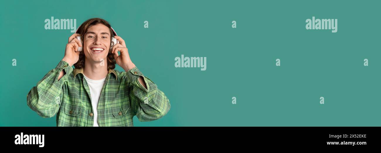 Happy guy with headset listening to favorite song on turquoise Stock Photo