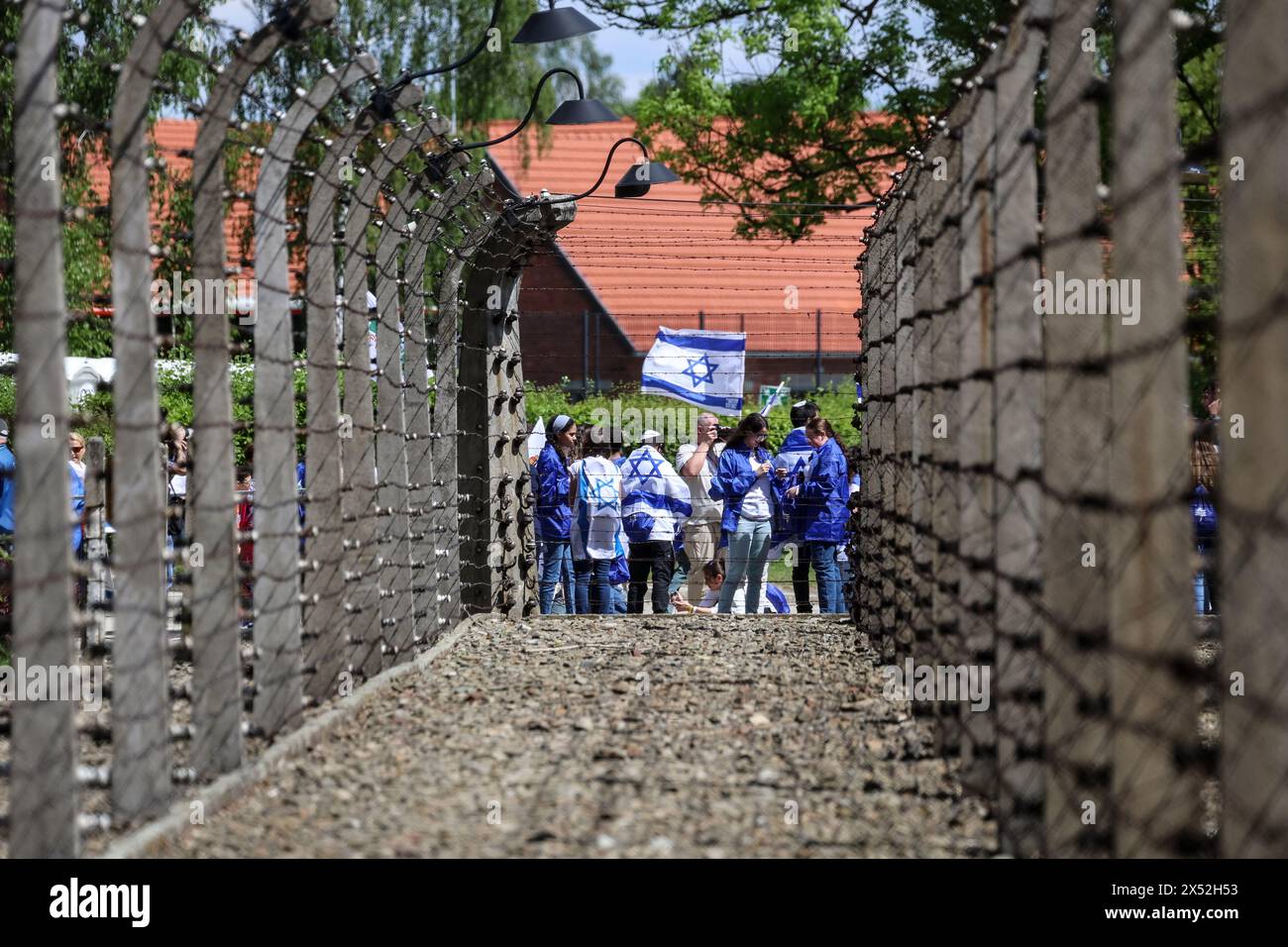 Oswiecim, Poland, May 6, 2024. Visitors walks past wired fence as they arrive for the March of the Living 2024 at Auschwitz Camp gate 'Work Makes you Free'Yoav Kisch, Minister of Education of Israel (C) visits exhibitions as he arrive for the March of the Living at Auschwitz Camp gate 'Work Makes you Free', with 55 Holocaust survivors participating. Holocaust survivors, and October 7th survivors attend the March of the Living together with a delegation from, among others, the United States, Canada, Italy, United Kingdom. On Holocaust Memorial Day observed in the Jewish calendar (Yom HaShoah), Stock Photo
