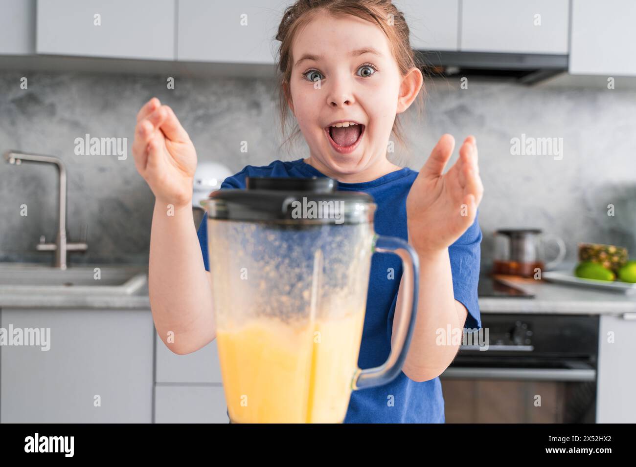 Portrait of a cheerful little girl with a blender in the kitchen. Crazy ...