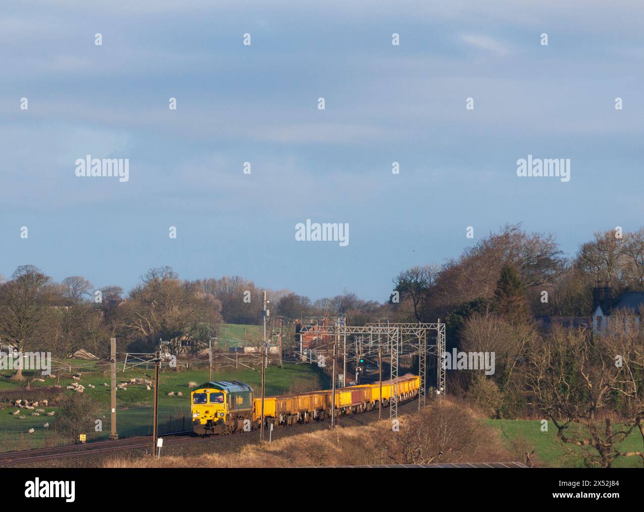 Freightliner Class 66  locomotive passing bay Horse on the west coast Mainline with a train carrying materials for Network Rail track renewal Stock Photo