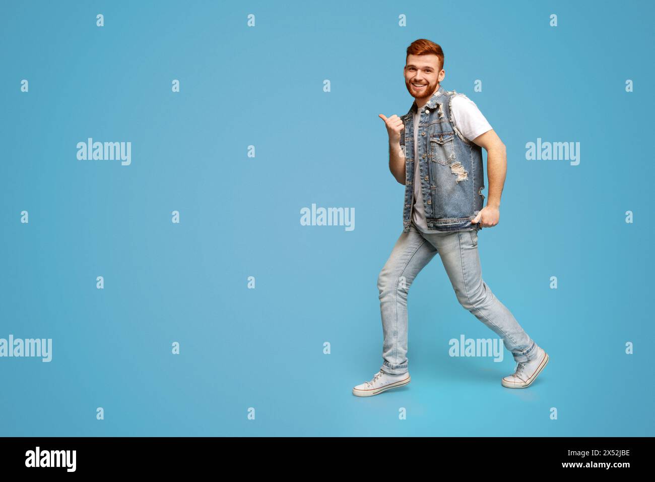 Cool millennial man dancing with thumbs up gestures in studio Stock Photo