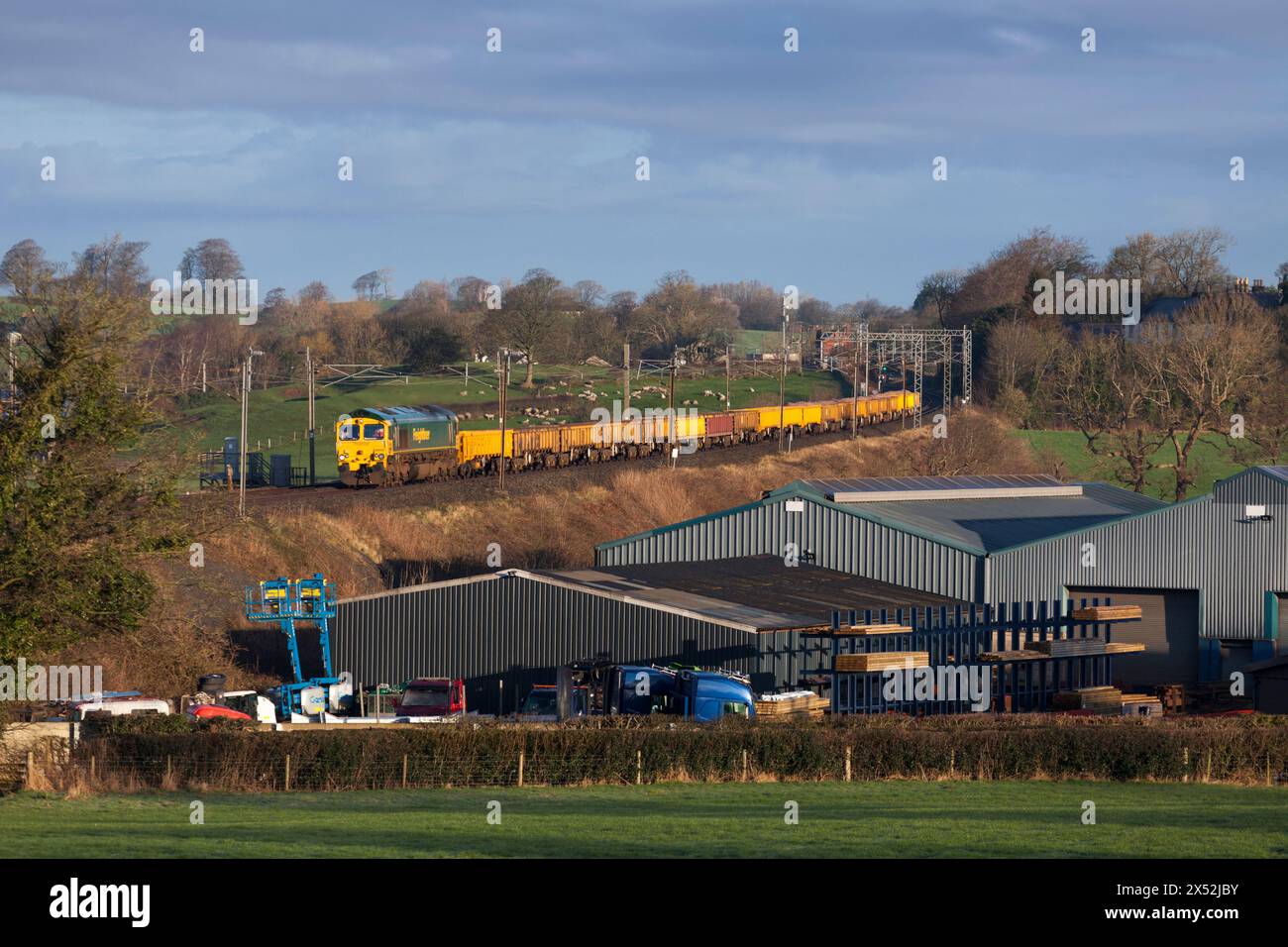 Freightliner Class 66  locomotive passing bay Horse on the west coast Mainline with a train carrying materials for Network Rail track renewal Stock Photo
