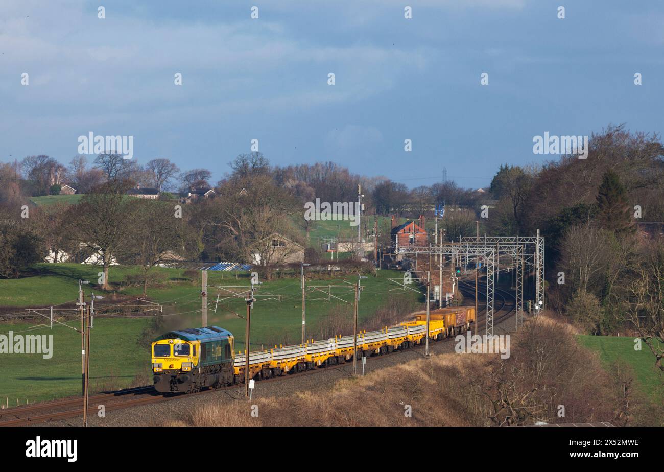 Freightliner Class 66  locomotive passing bay Horse on the west coast Mainline with a train carrying materials for Network Rail track renewal Stock Photo