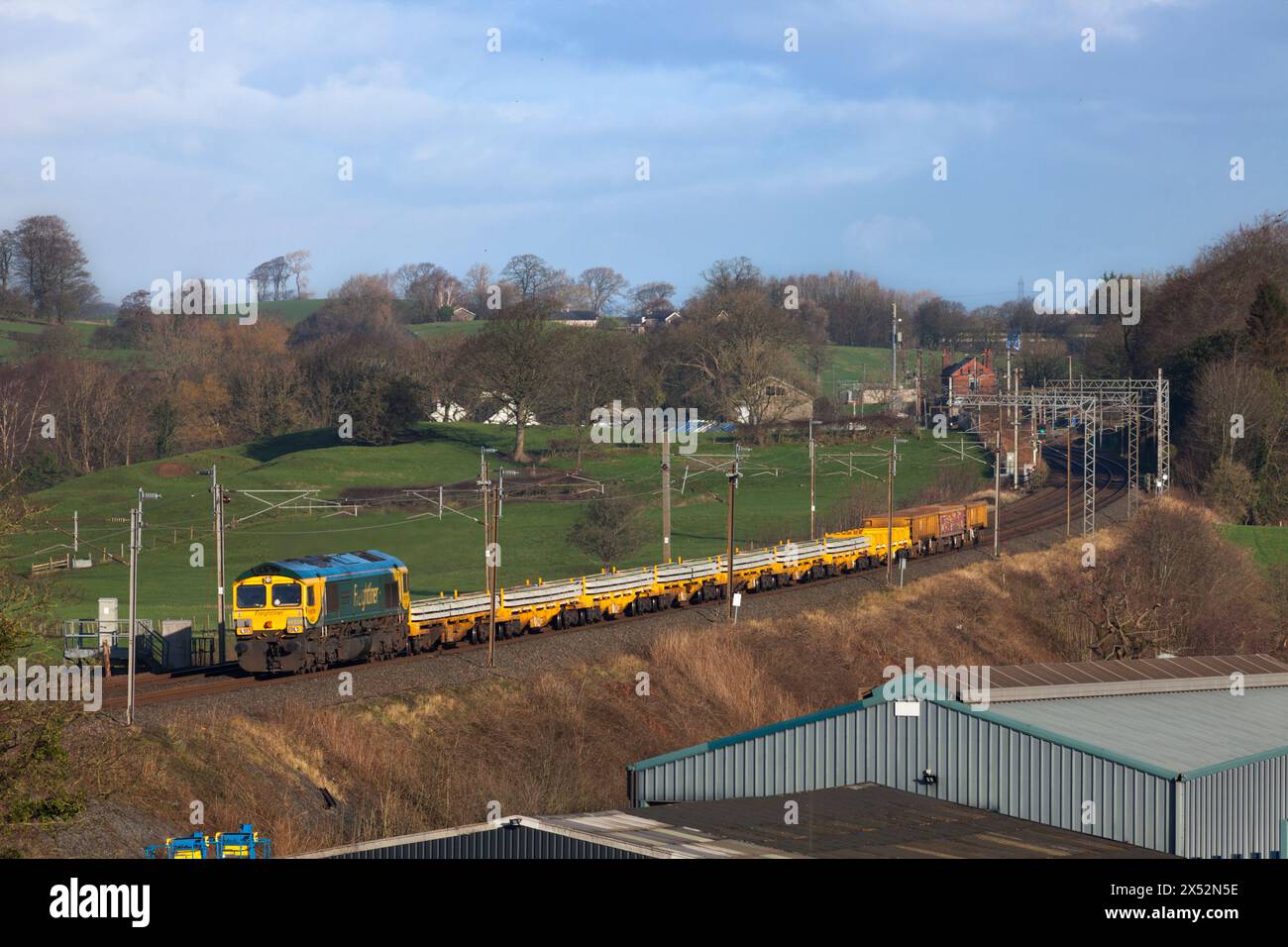 Freightliner Class 66  locomotive passing bay Horse on the west coast Mainline with a train carrying materials for Network Rail track renewal Stock Photo