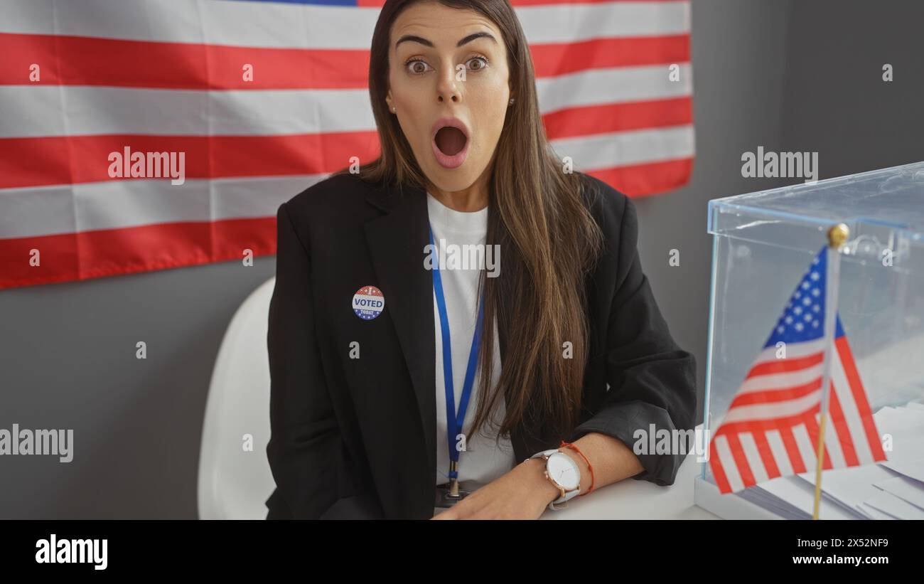 Shocked latina woman with 'i voted' sticker indoors near american flag and ballot box Stock Photo