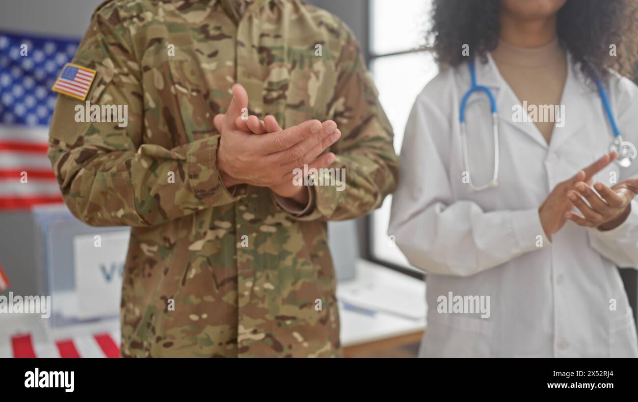 A man in military uniform and a woman in medical attire applauding indoors with a usa flag in the background. Stock Photo