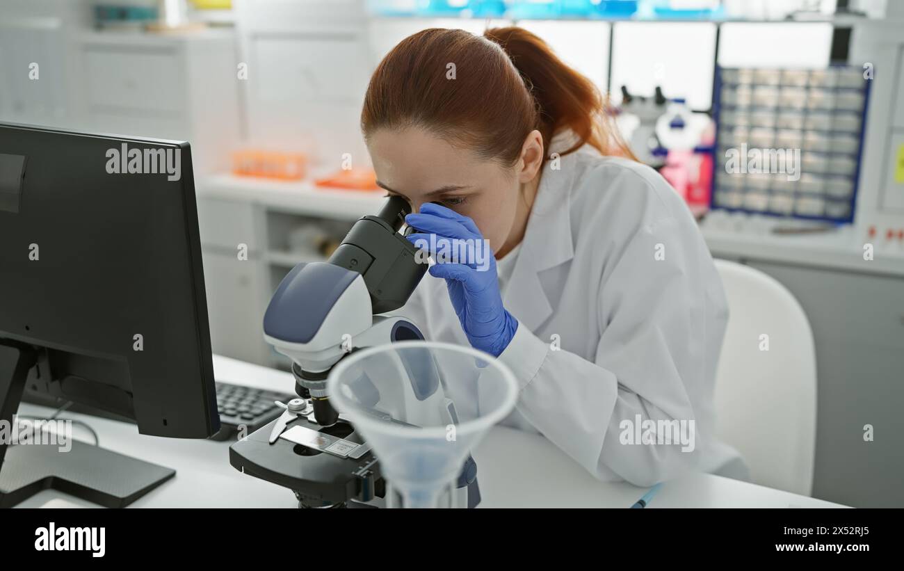 A focused caucasian woman scientist analyzing samples using a microscope in a laboratory Stock Photo