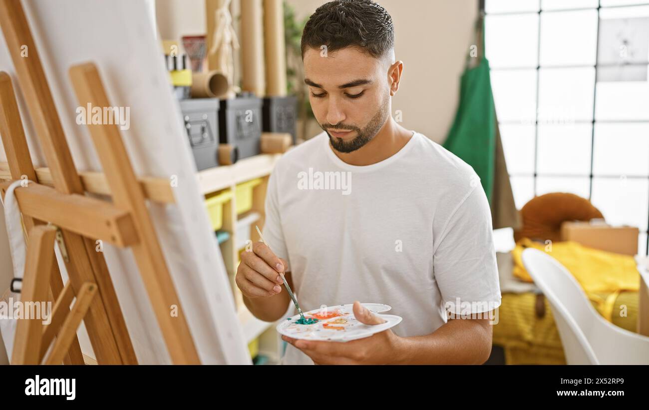 A focused young man painting on canvas in an art studio, embodying ...