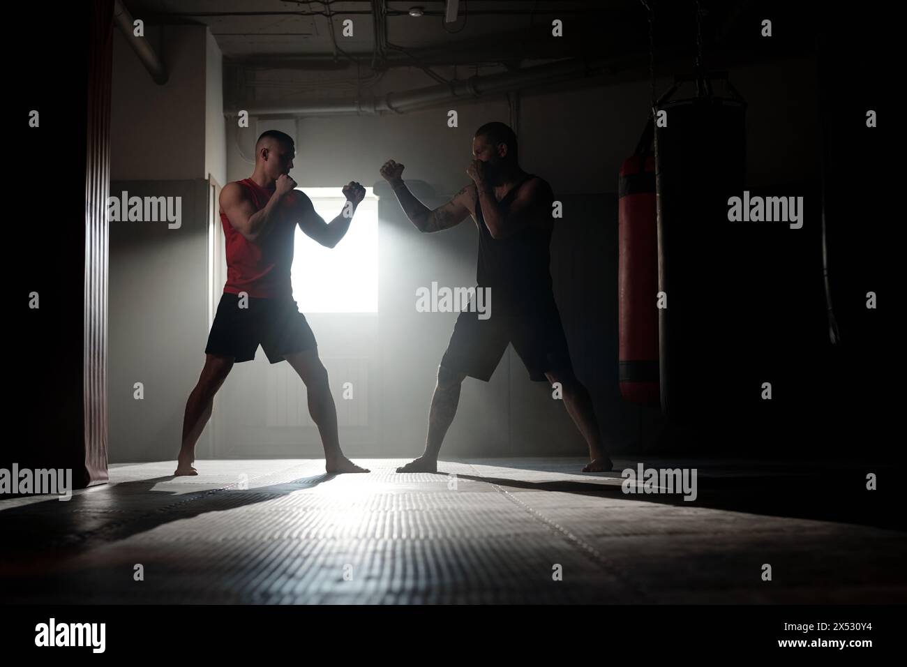 Two backlit male figures with clenched fists standing in front of one