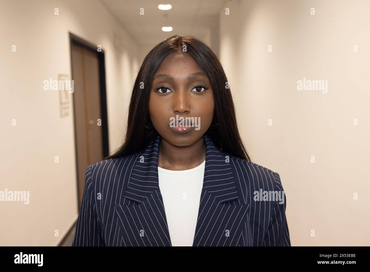 An African American woman stands confidently in a brightly lit office ...