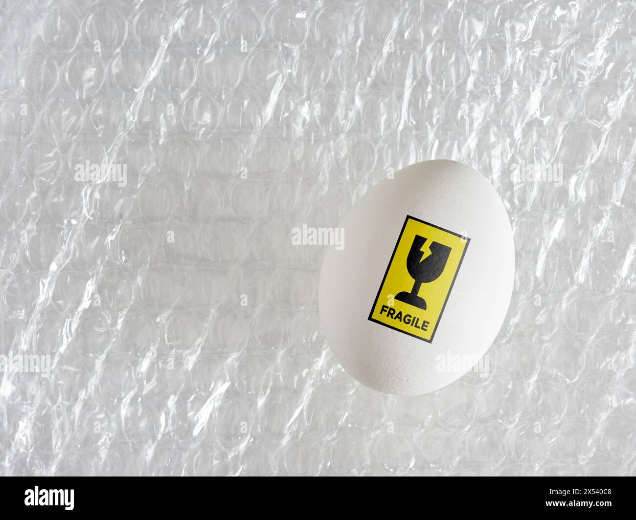 Packaging and delivery of fragile goods. Transportation and delivery with care. Egg with fragile sticker on a bubble wrap. Stock Photo