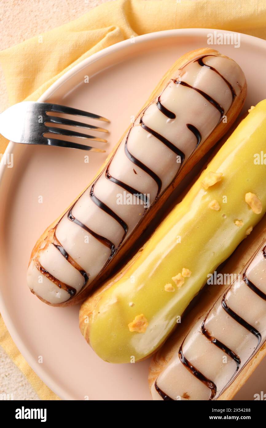 Different tasty glazed eclairs served on table, top view Stock Photo
