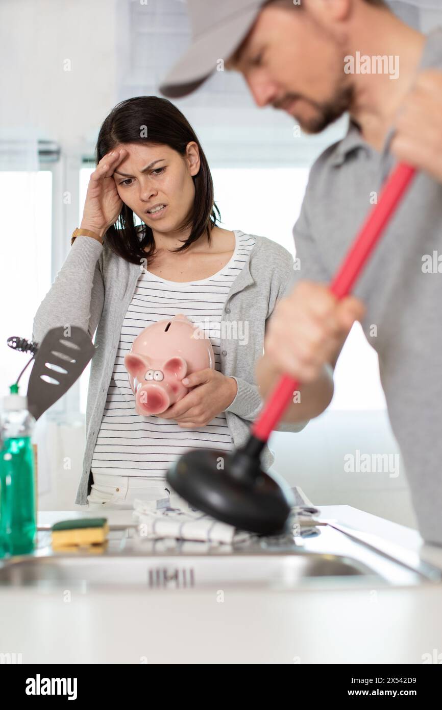 cleaning clogged pipes in the kitchen sink with a plunger Stock Photo
