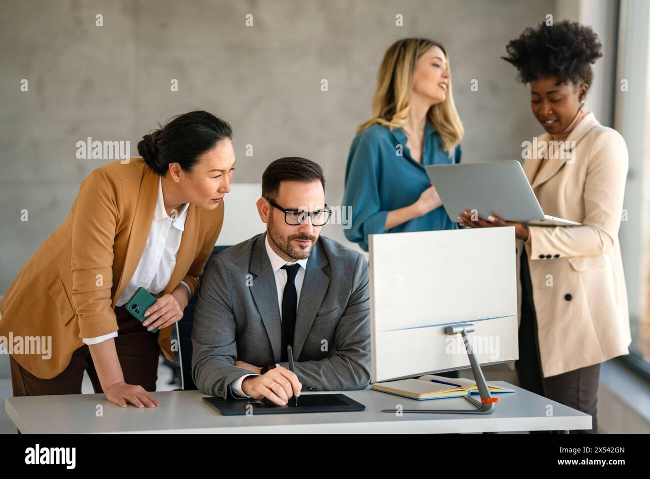 Senior business manager talking with experienced colleague while using computer in office. Stock Photo
