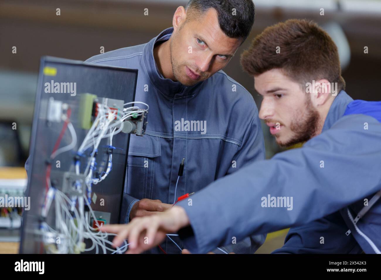 technician and apprentice repairing television mounted on wall Stock
