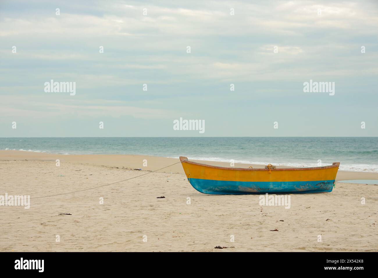 Old wooden fishing boat in blue and yellow colors on white sand beach ...