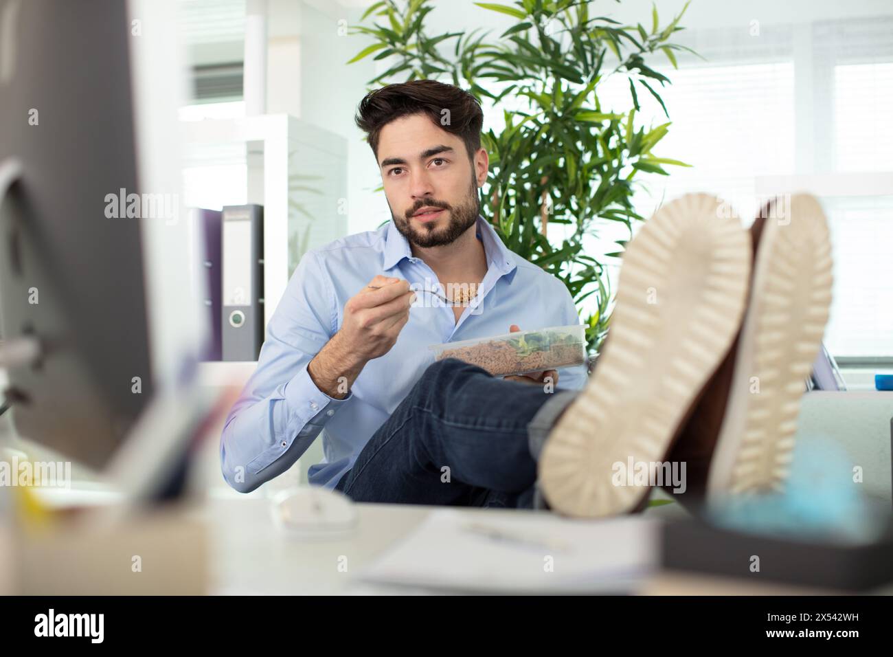 thoughtful man sitting with feet on table in office Stock Photo