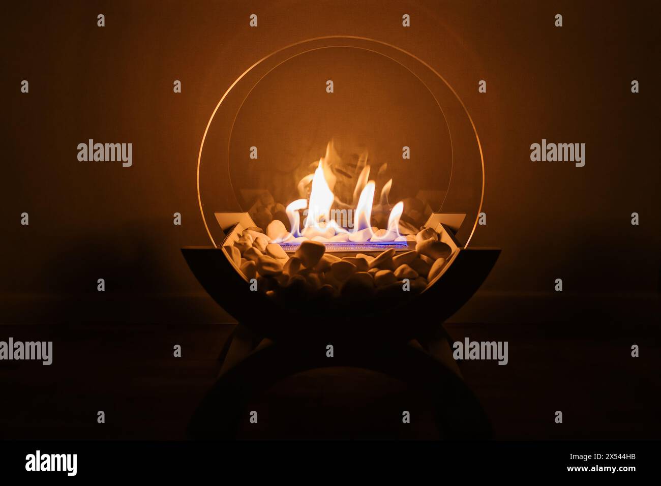 Decorative fireplace with white stones and glass panels standing on the floor in the room Stock Photo