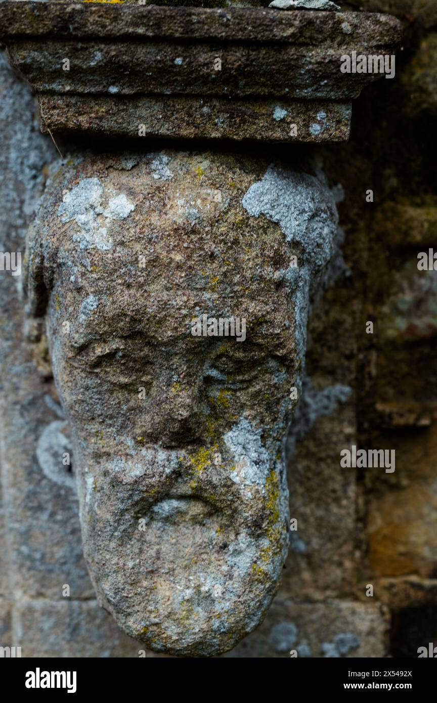 Close-up of a weathered stone corbel head at the base of a church door arch, Herstmonceux, East Sussex Stock Photo