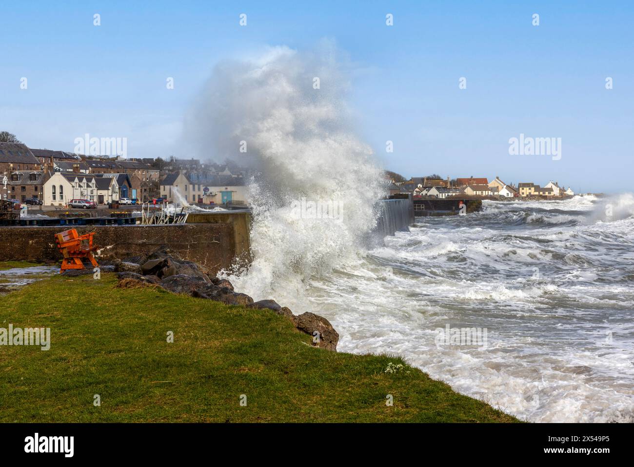 The fishing village of Johnshaven, situated in Aberdeenshire, Scotland, during a stormy day, with waves crashing against its harbour walls. Stock Photo