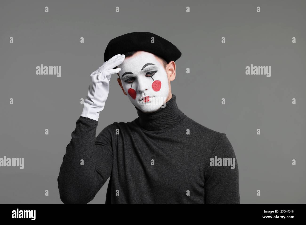 Mime artist in beret posing on grey background Stock Photo