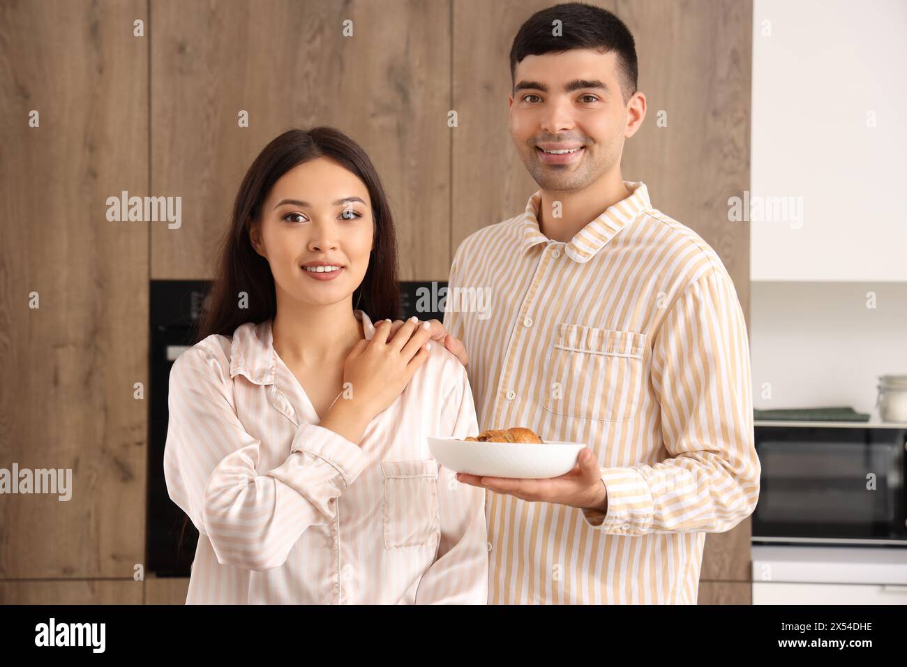 Happy young couple having breakfast in kitchen Stock Photo