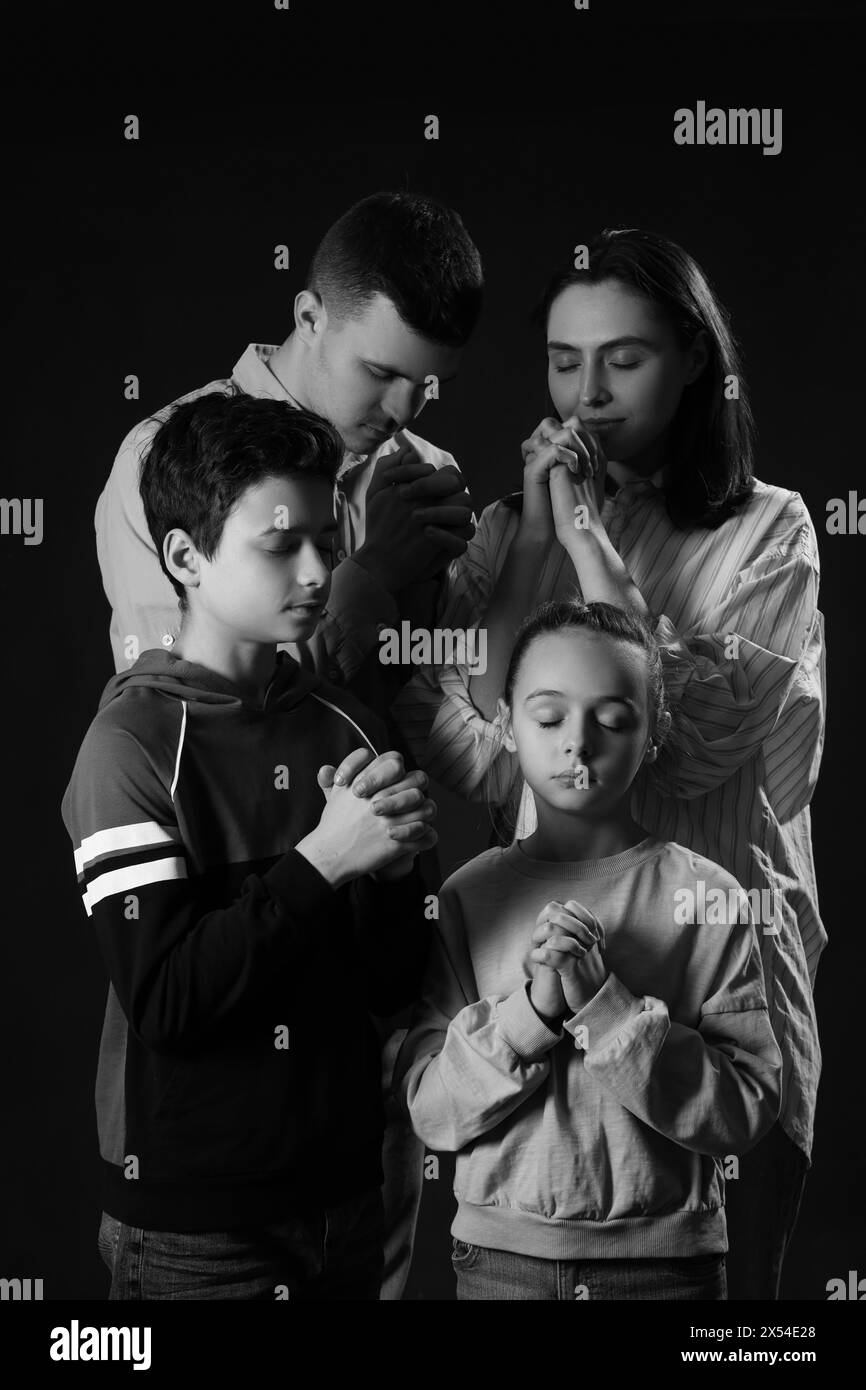 Family praying together on dark background Stock Photo