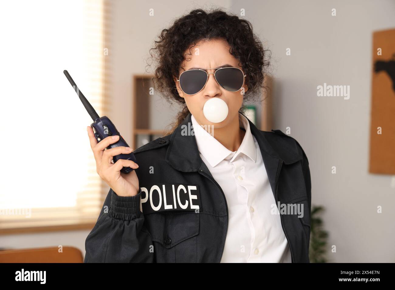 African-American police officer with radio transmitter blowing bubble ...