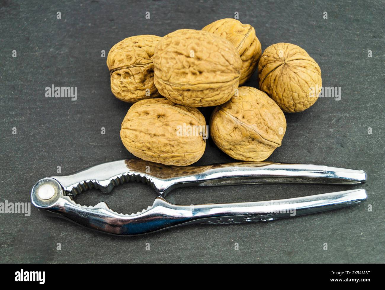 walnut (Juglans regia), Walnuts on a black background with nutcracker Stock Photo