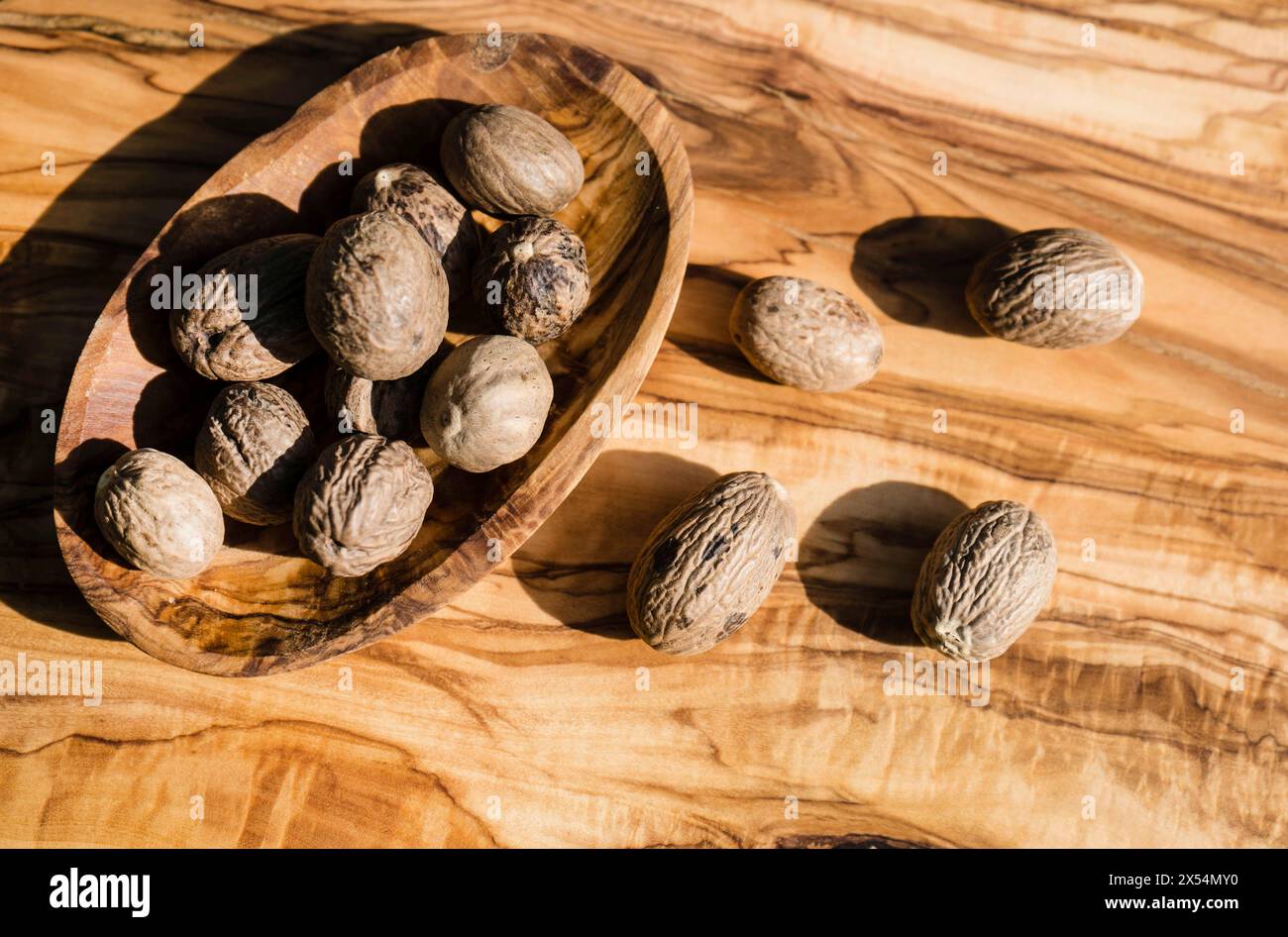 nutmeg, mace (Myristica fragrans), nutmegs in a wooden bowl on a wooden table Stock Photo