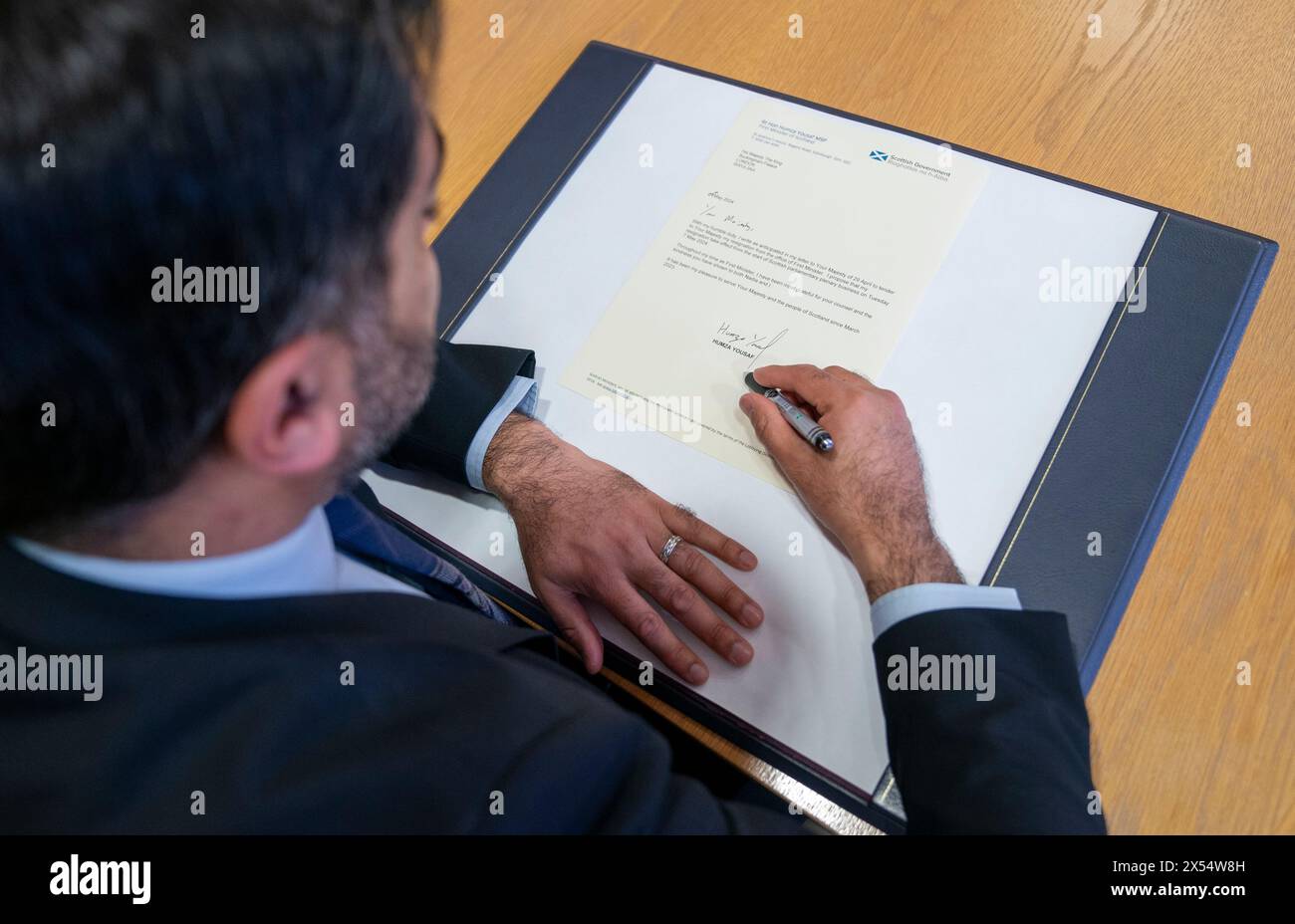 Outgoing First Minister Humza Yousaf signs his official resignation letter to King Charles III at the Scottish Parliament in Edinburgh. Picture date: Tuesday May 7, 2024. Stock Photo
