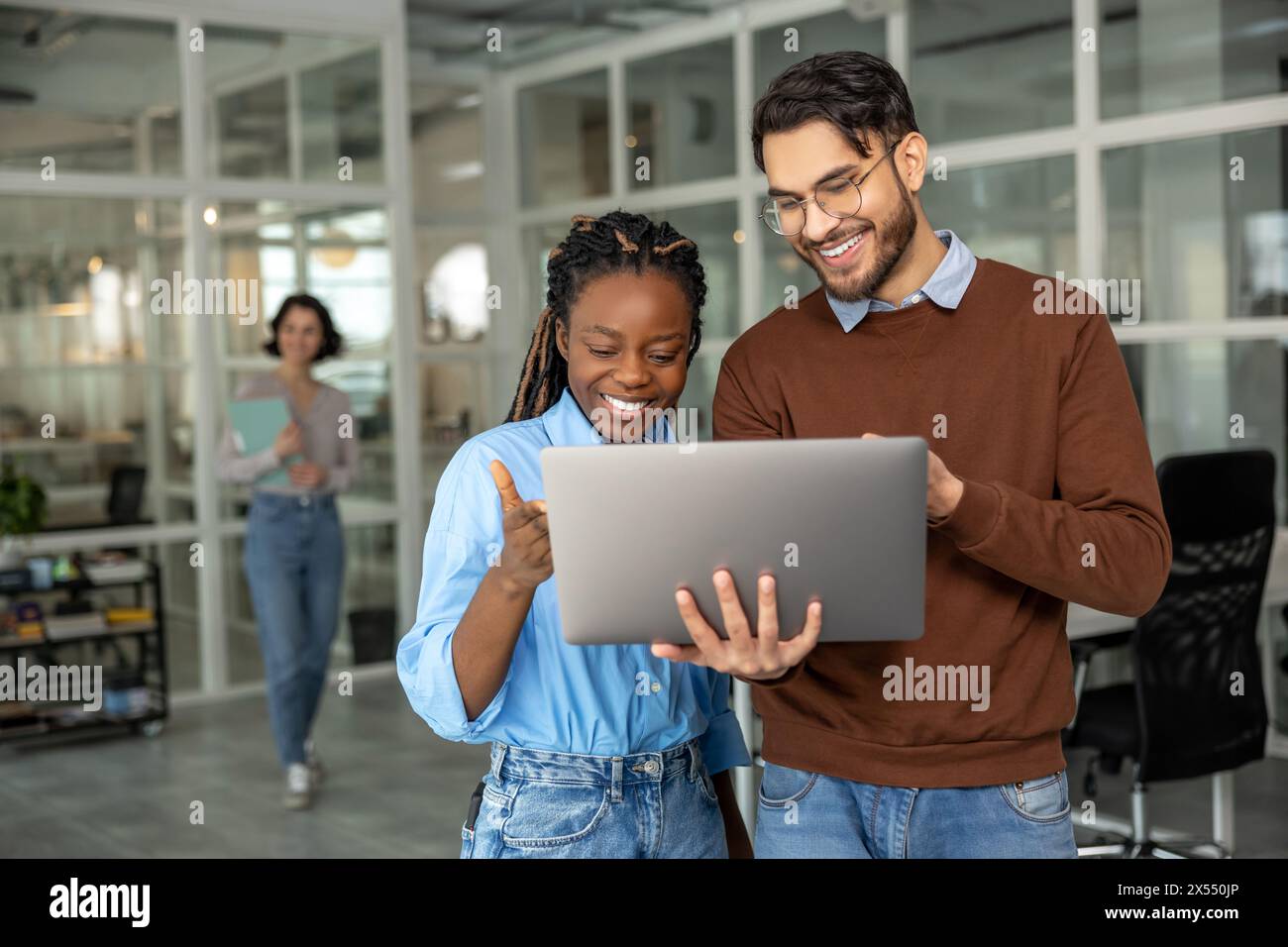 Diverse colleagues collaborating on project together using laptop Stock Photo