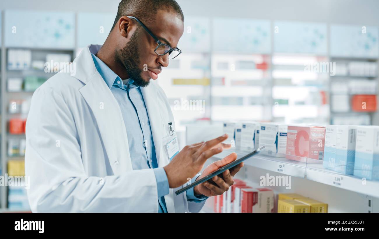 Pharmacy: Portrait of Professional Black Pharmacist Uses Digital Tablet Computer, Checks Inventory of Medicine, Drugs, Vitamins on a Shelf. Druggist in Drugstore Store Arranging Health Care Products Stock Photo