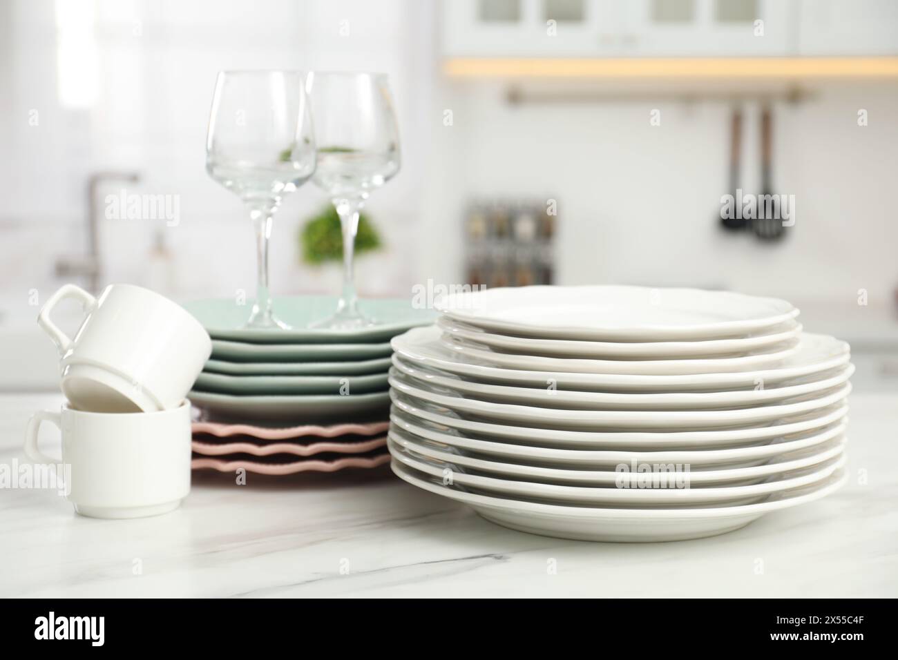 Clean plates, cups and glasses on white marble table in kitchen Stock ...