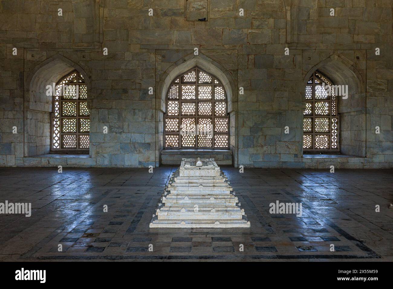 the white marble sarcophagus of hoshang shah in foront of three arched lattice windows inside his mausoleum Stock Photo