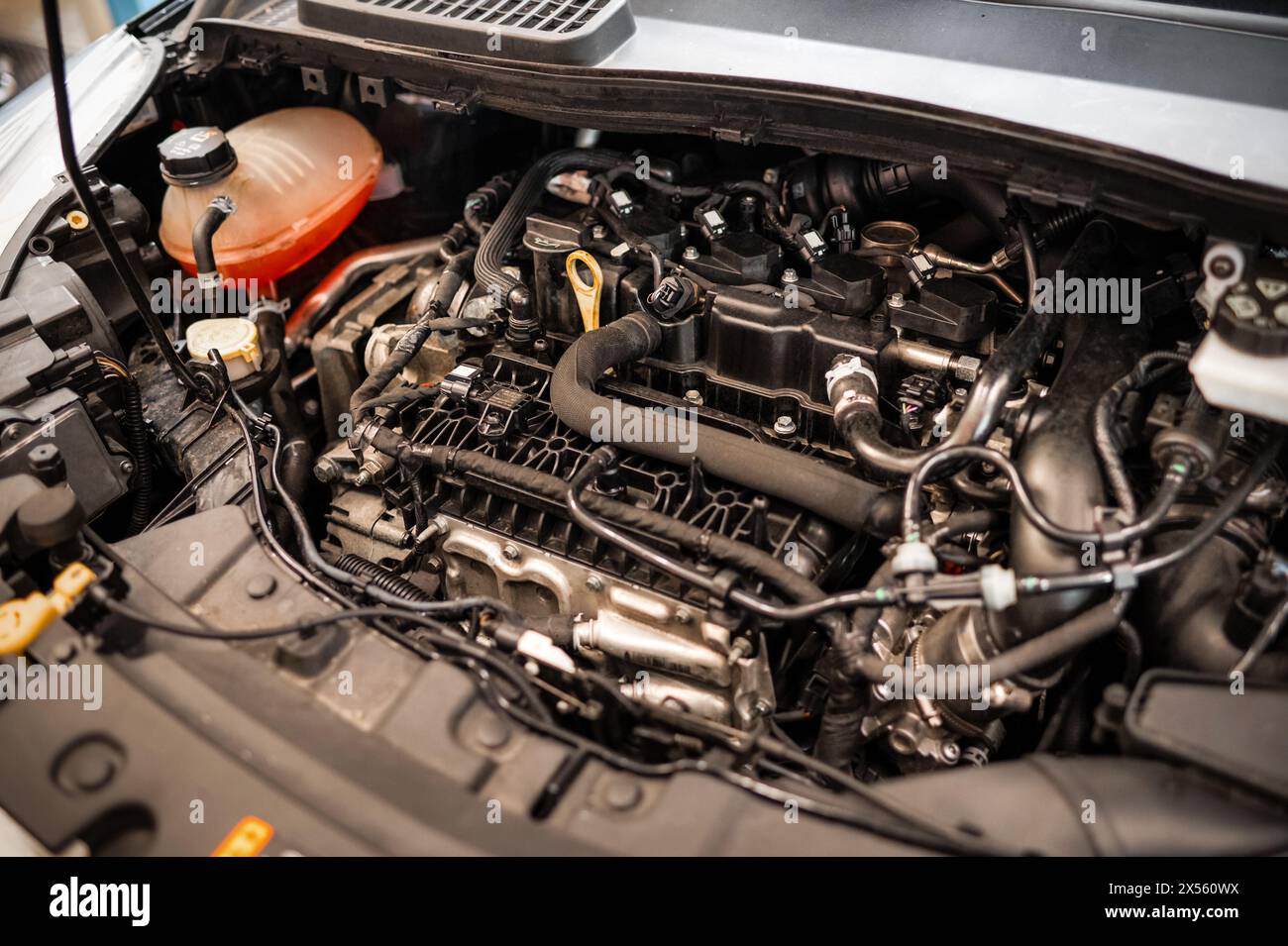 From above visible dusty car engine under opened hood with various assembled spare parts while electric cables connected with battery and in service s Stock Photo